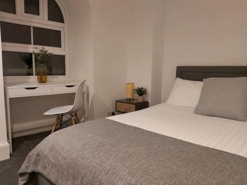 een slaapkamer met een bed, een bureau en een raam bij The Cozy Landport Loft in Portsmouth