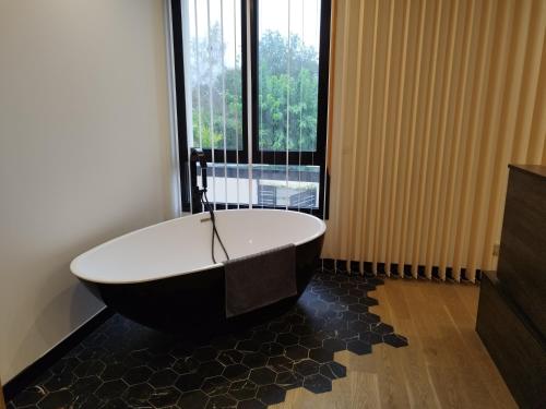 eine Badewanne in einem Zimmer mit einem großen Fenster in der Unterkunft VILLA CONTEMPORAINE in Voulangis