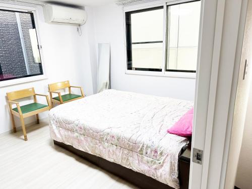 - une chambre avec un lit et deux chaises dans l'établissement 花乃郷 本郷, à Tokyo