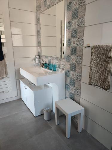 La salle de bains est pourvue d'un lavabo, d'un miroir et d'un tabouret. dans l'établissement Les Terrasses du Phenix, à Saint Alban Auriolles