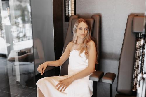 a woman in a white dress sitting on a chair at ONKL XONNA Premium Alpin Chalets in Hüttschlag