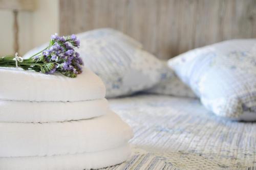 a stack of towels with a bouquet of flowers on a bed at Triantafilia Guesthouse in Áyioi Apóstoloi