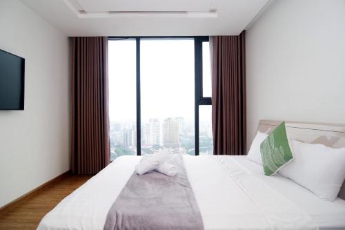 a bedroom with a white bed with a large window at QMP - Vinhomes Metropolis in Hanoi