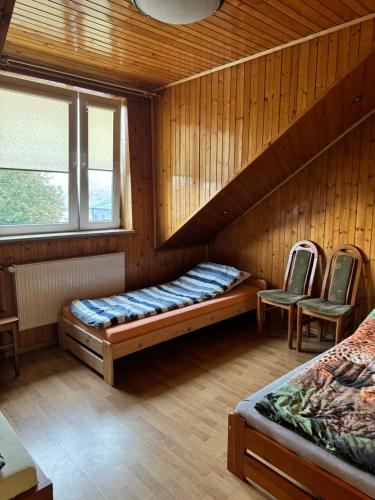 a room with two beds and two chairs at Agroturystyka Działoszyce in Działoszyce