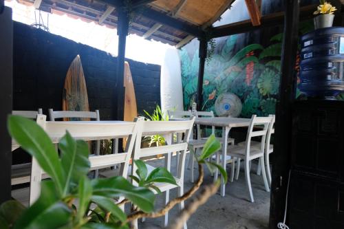 a dining room with tables and chairs and surfboards on the wall at Surf Camp 79 in Kuta Lombok