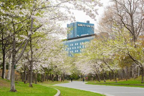 a path through a park with trees and a building at Sapporo Park Hotel in Sapporo