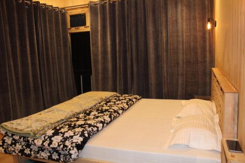 a bed sitting in a room with a window at THE GROOVE GARDEN DHANOLTi in Dhanaulti