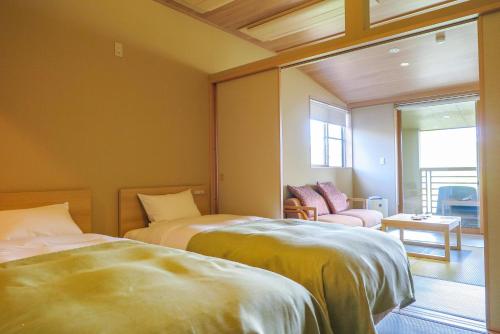 a bedroom with two beds and a window and a chair at Nagisatei Taroan in Miyako
