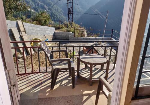 a balcony with two chairs and a table and a view at The Royal Orchard Homestay by StayApart in Nārkanda