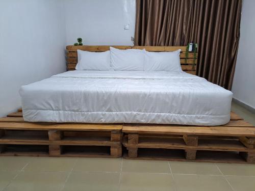 ein Bett auf einer hölzernen Plattform mit einer weißen Matratze in der Unterkunft Igbalode Luxury Apartment in Ibadan