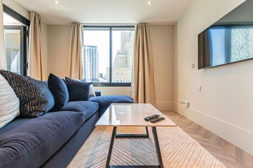 a living room with a blue couch and a glass table at Luxurious 1 Bed - CITY VIEW in Liverpool