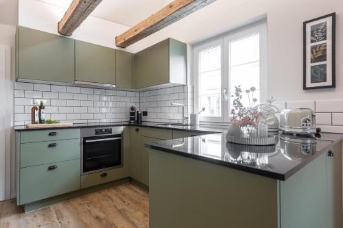 黑里紹的住宿－Dein Zuhause in Herisau，厨房配有绿色橱柜和台面