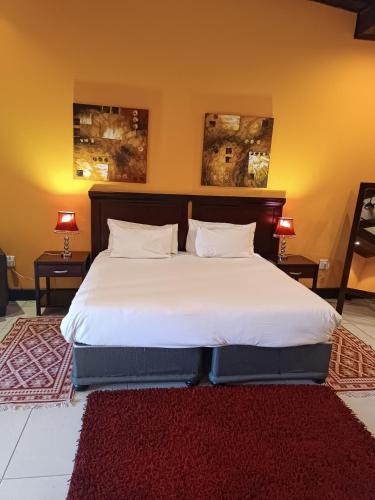 a bedroom with a large white bed with a red rug at Riverstone Lodge in Muldersdrift