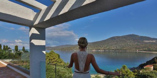 a woman standing on a balcony looking out at a lake at A'mare Corsica I Seaside Small Resort in Propriano