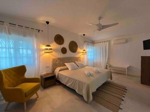 a bedroom with a bed and a yellow chair at Villa Jiménez in Griñón