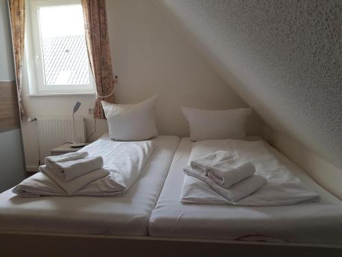 a bed with white sheets and towels on it at Kogge in Wittdün