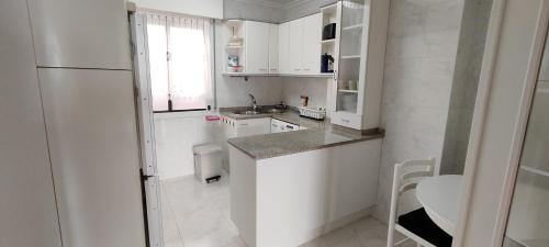 蒙達卡的住宿－Mundaka Izaro Eye，厨房配有白色橱柜和白色冰箱。