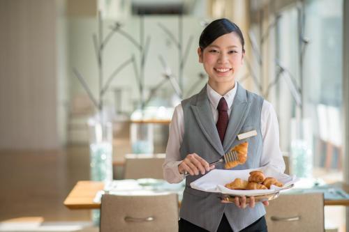 a woman is holding a plate of pastries at Sapporo Park Hotel in Sapporo