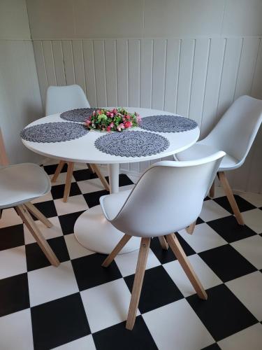 a table with white chairs and a flower arrangement on it at Hietaman Vierastalo Marilyn in Äänekoski