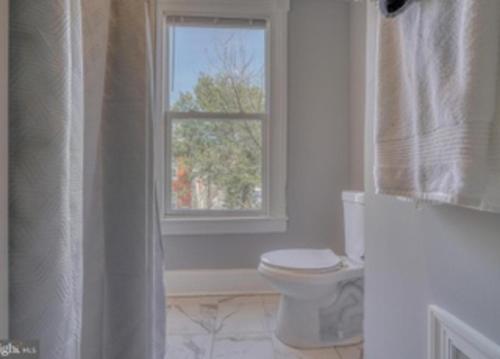 a white bathroom with a toilet and a window at Budget Bed Room near Downtown Inner Harbor w Free Parking in Baltimore