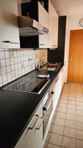 una cocina con armarios blancos y encimeras negras en Zweite Heimat Bamberg, en Stegaurach