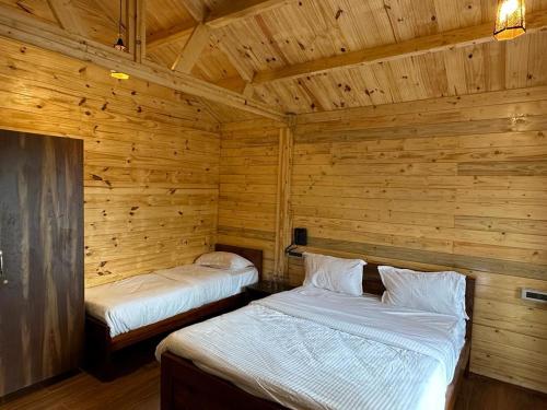 two beds in a room with wooden walls at Coorg Jungle Mist in Madikeri