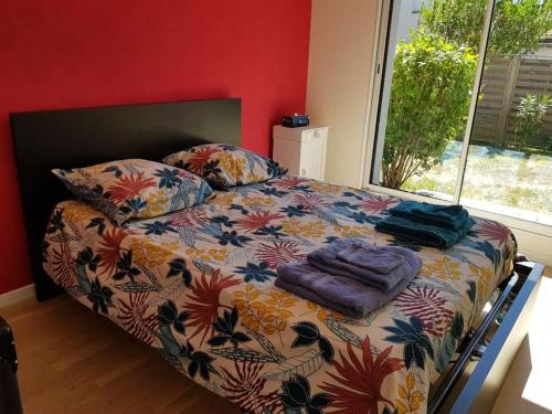 a bedroom with a bed with a floral comforter and a window at 9 pers 160 M² +jardin- 10mn Nantes -30mn mer in Bouguenais