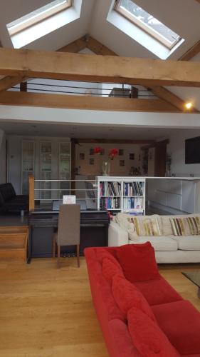 a living room with a red couch and some windows at Prestwick Oak - Sleeps 10-14 - Group Accommodation for Family or Friends in Haslemere