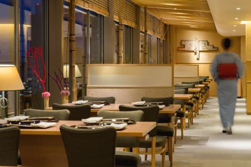 a person walking through a dining room with tables and chairs at Sapporo Park Hotel in Sapporo
