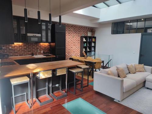 une cuisine et un salon avec un canapé et une table dans l'établissement Loft Paris centre face au parc des buttes Chaumont, à Paris