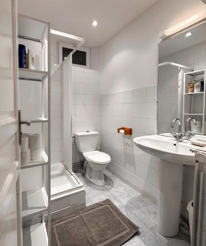 a white bathroom with a toilet and a sink at Le cottage de David in Pierrefonds