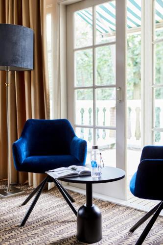 a living room with a blue chair and a table at Kasteel Kerckebosch in Zeist