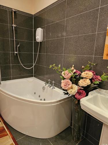 a bathroom with a tub and a vase of flowers at Baron Park House in Clonmel