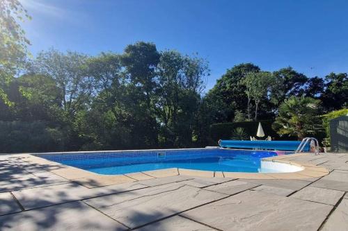 a swimming pool with blue water in a yard at Woodpeckers - Alresford Essex in Alresford
