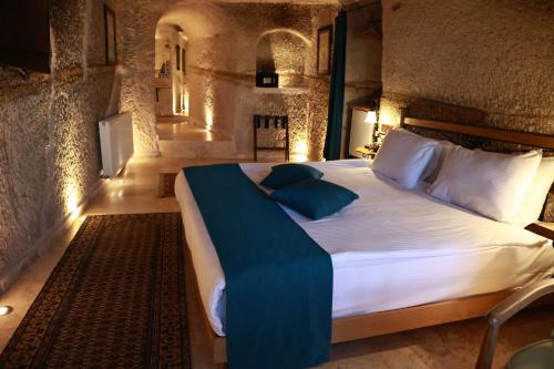 a bedroom with a large white bed with blue pillows at Peruna Cave in Goreme