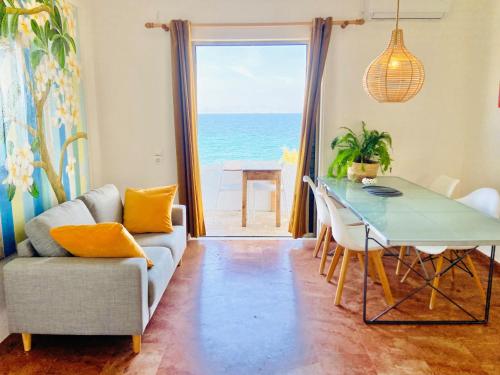 a living room with a table and a view of the ocean at The Beachhouse Apartments in Vaia