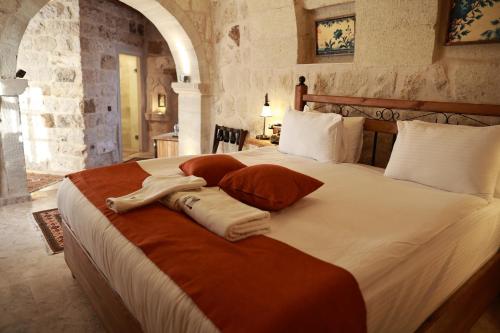 a bedroom with a large bed with white sheets and pillows at Peruna Cave in Goreme