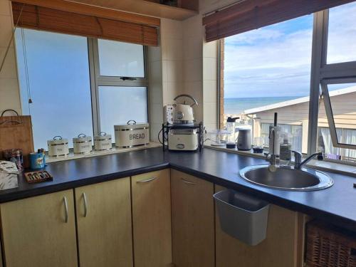 een keuken met een spoelbak en uitzicht op de oceaan bij Captains View in Jeffreys Bay