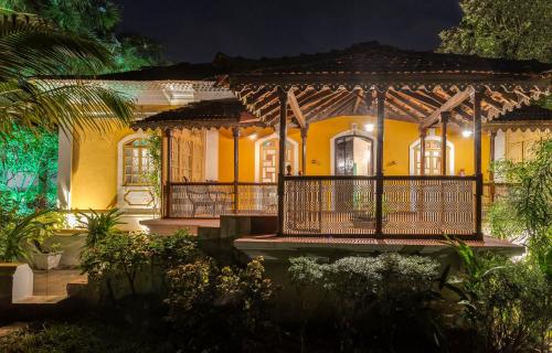 a yellow house with a porch at night at Villa Sereno by Insignia Villas in Assagao