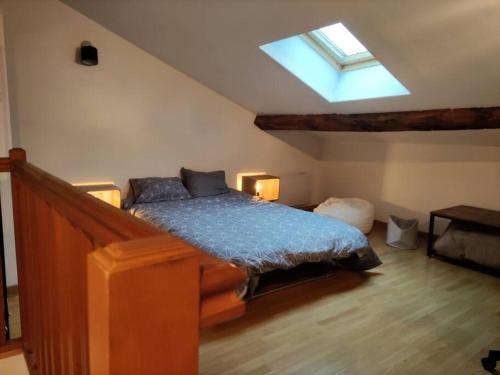 een slaapkamer met een bed en een dakraam bij L'Atelier Cosy - Maison de village Atypique in Saint-Georges-dʼEspéranche