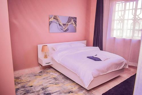 a bedroom with a white bed and a window at EnZ lovely 2 bedroom Apartment Milimani Nakuru in Nakuru