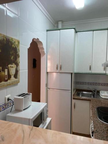 La cuisine est équipée d'un réfrigérateur blanc et d'un four micro-ondes. dans l'établissement Nice apartment Torrecilla Beach, à Nerja