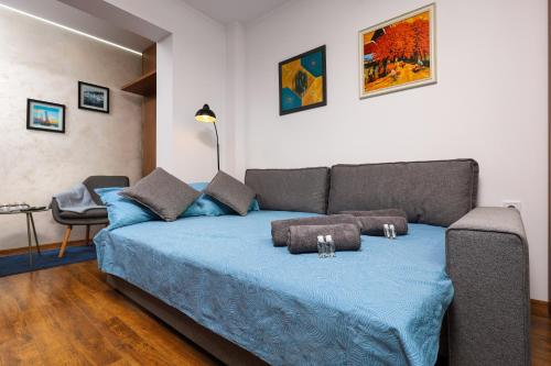 ein Schlafzimmer mit einem Bett mit blauer Bettwäsche und einem Sofa in der Unterkunft Studio Maria- Prime Location in Kapana District in Plowdiw