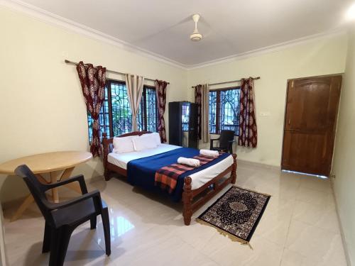 a bedroom with a bed and a table and a desk at Pappa's Guest House in Arambol