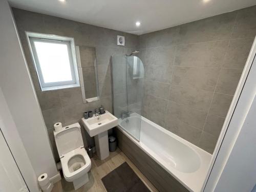 a bathroom with a toilet and a sink and a bath tub at 3 Bedroom New House with Wi-Fi Sleep 5 By Home Away From Home in Newcastle under Lyme