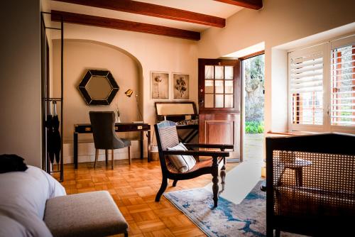 a bedroom with a desk and a chair and a table at Blaauwklippen Manor by NEWMARK in Stellenbosch