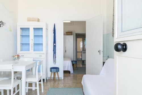 - un salon avec une table et des chaises blanches dans l'établissement Casa Helios, à Villanova di Ostuni