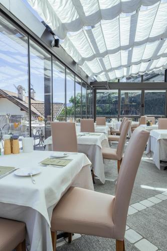 a restaurant with white tables and chairs and windows at DAS BADL - Smart Retreat AO in Caldaro