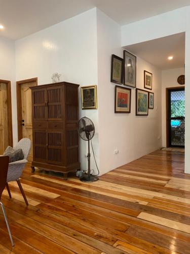 a living room with a wooden floor and a fan at Balai Benedicere Bed & Breakfast in Bacnotan