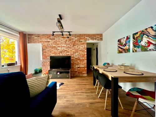 a living room with a table and a brick wall at Apartament Centrum Słupsk,WiFi-Netflix,dzieci I zwierzeta mile widziane! in Słupsk